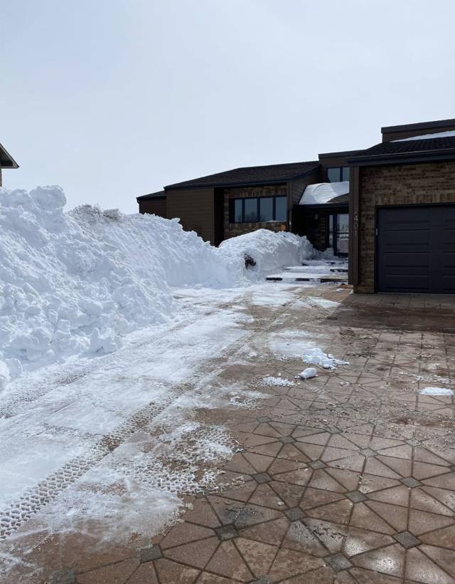 Paver driveway cleared of snow with the snow pushed into a tall pile